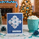 Card with decorative winter design next to a teal mug with hot chocolate and marshmallows, set against a festive background. Christmas cards, nesting dies, Christmas dies, nested dies, square die cuts, stitched dies, blue winter card, scrapbooking, card making
